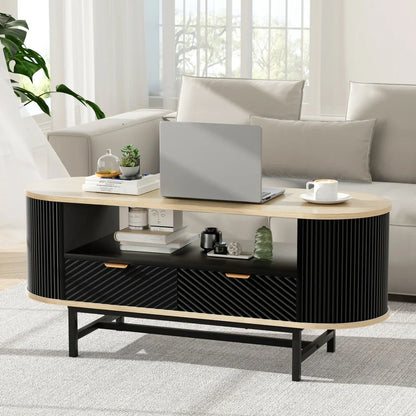 Modern oval coffee table with laptop, books and decor in a bright living room
