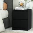 Modern black nightstand with two drawers beside bed, topped with books, vase, and decor orb