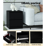 Modern black bedside table with two deep drawers, next to grey sofa, minimal decor.