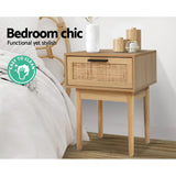 Modern wooden bedside table with rattan drawer and decor in a stylish bedroom, easy to clean