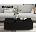 Minimalist modern black coffee table with plant and books in front of grey sofa