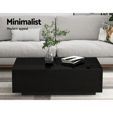 Minimalist modern black coffee table with plant and books in front of grey sofa