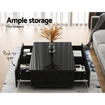 Modern black coffee table with glossy finish, four push-to-open drawers, and decorative vase.