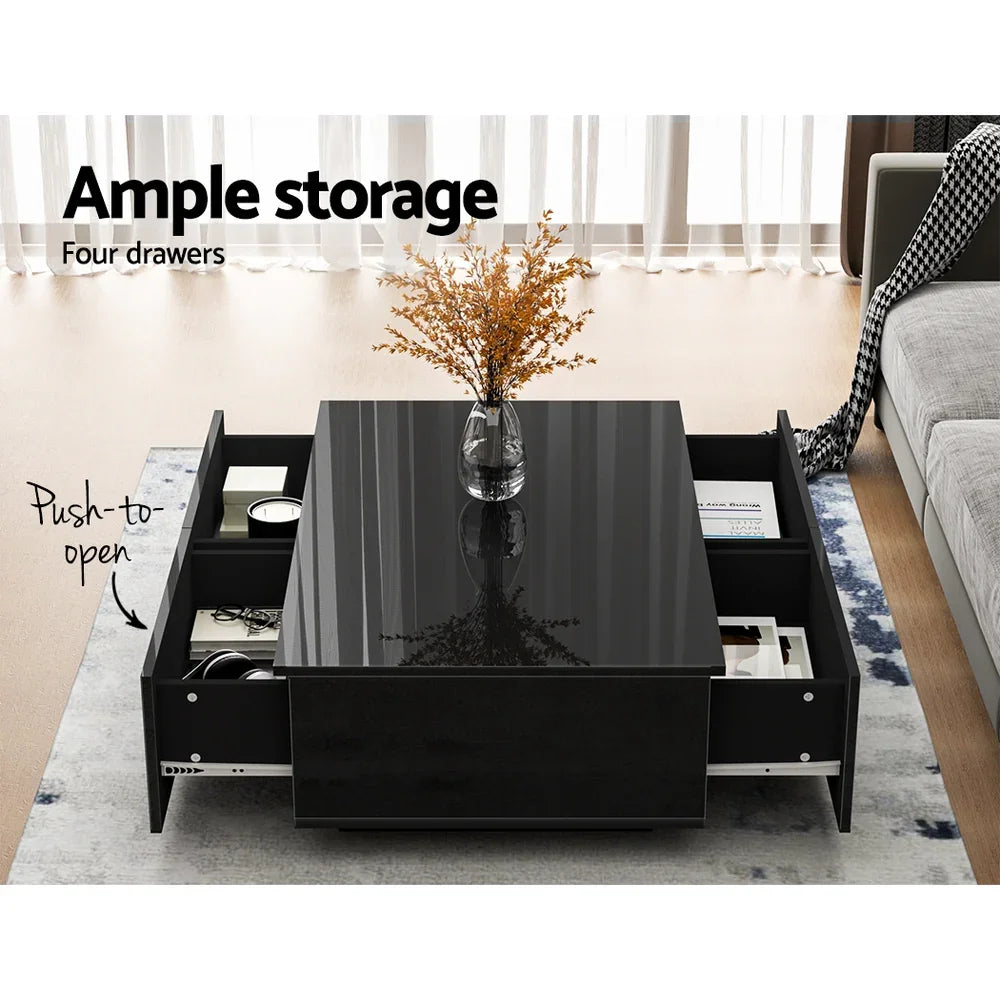 Modern black coffee table with glossy finish, four push-to-open drawers, and decorative vase.