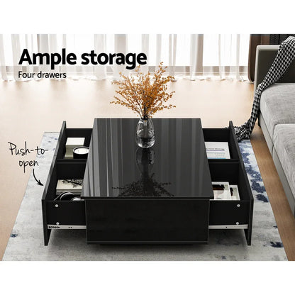 Modern black coffee table with glossy finish, four push-to-open drawers, and decorative vase.