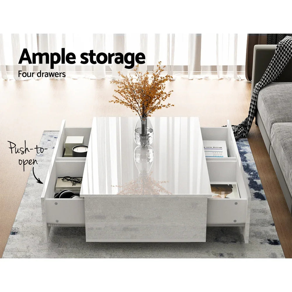 Modern white coffee table with four push-to-open storage drawers and glass vase decor