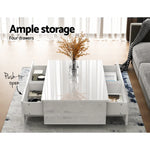 Modern white coffee table with four push-to-open storage drawers and glass vase decor