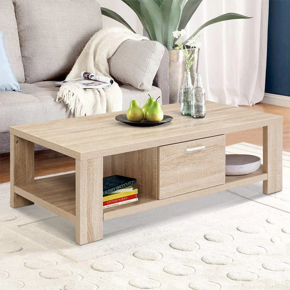 Modern light wood coffee table with drawer, books, and decor in a cozy living room setting