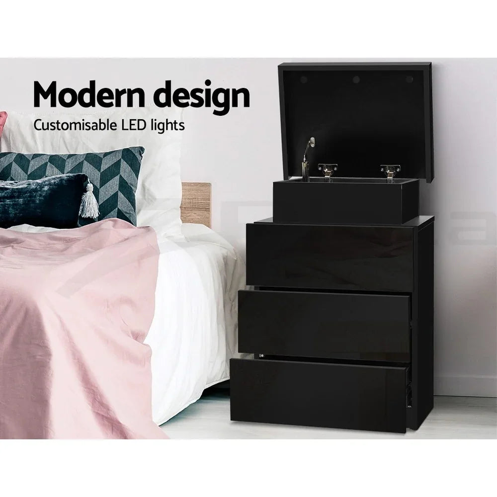 Modern black bedside table with customizable LED lights and open drawers beside a bed