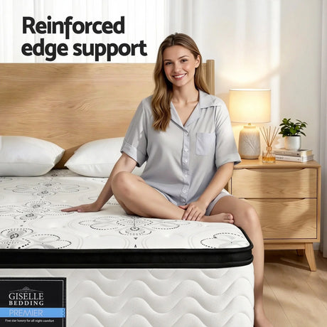 Woman sitting on Giselle Bedding Premier mattress with reinforced edge support in modern bedroom