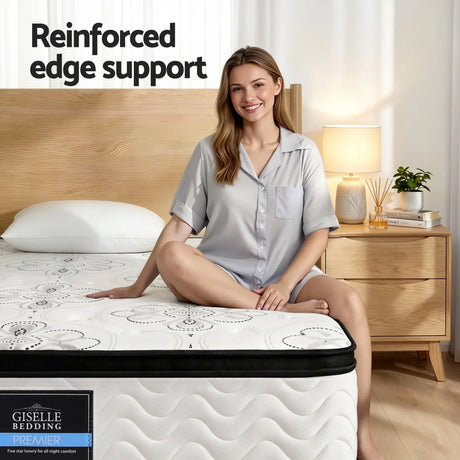 Woman sitting on Giselle Bedding Premier mattress with reinforced edge support in bedroom