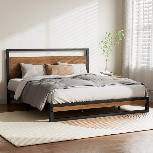 Modern bed frame with wood and black metal accents, gray bedding, beige pillow, and potted plant in bright bedroom