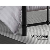 Black metal bed frame legs on gray textured rug with white striped bedding corner