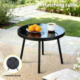 Outdoor black round bistro table with glass top on patio, holding oranges and a coffee cup, sturdy design