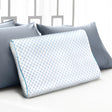 White contoured memory foam pillow with blue honeycomb pattern on bed with gray pillows