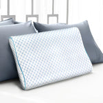White contoured memory foam pillow with blue honeycomb pattern on bed with gray pillows