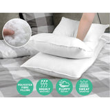 White polyester fiber-filled pillows on bed with hand touching one, emphasizing breathability, fluffiness, and sweat absorption