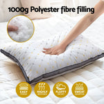 Hand pressing soft white pillow with polyester fiber filling on bed, highlighting breathability and sweat absorption