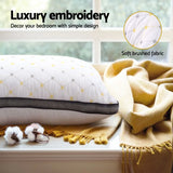 White luxury embroidered pillow with yellow accents on window sill next to soft brushed mustard yellow blanket