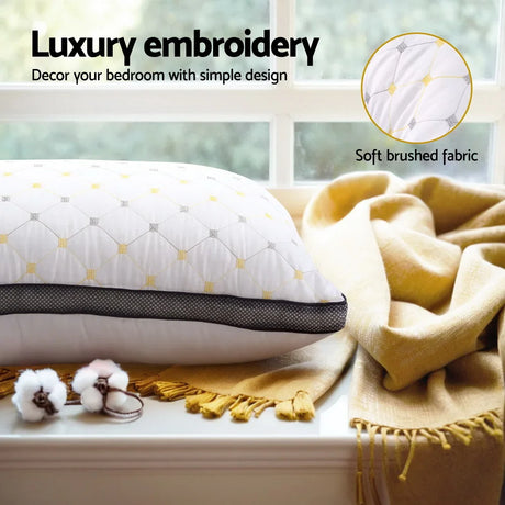 Luxury embroidered white pillow with yellow accents on mustard throw blanket by window