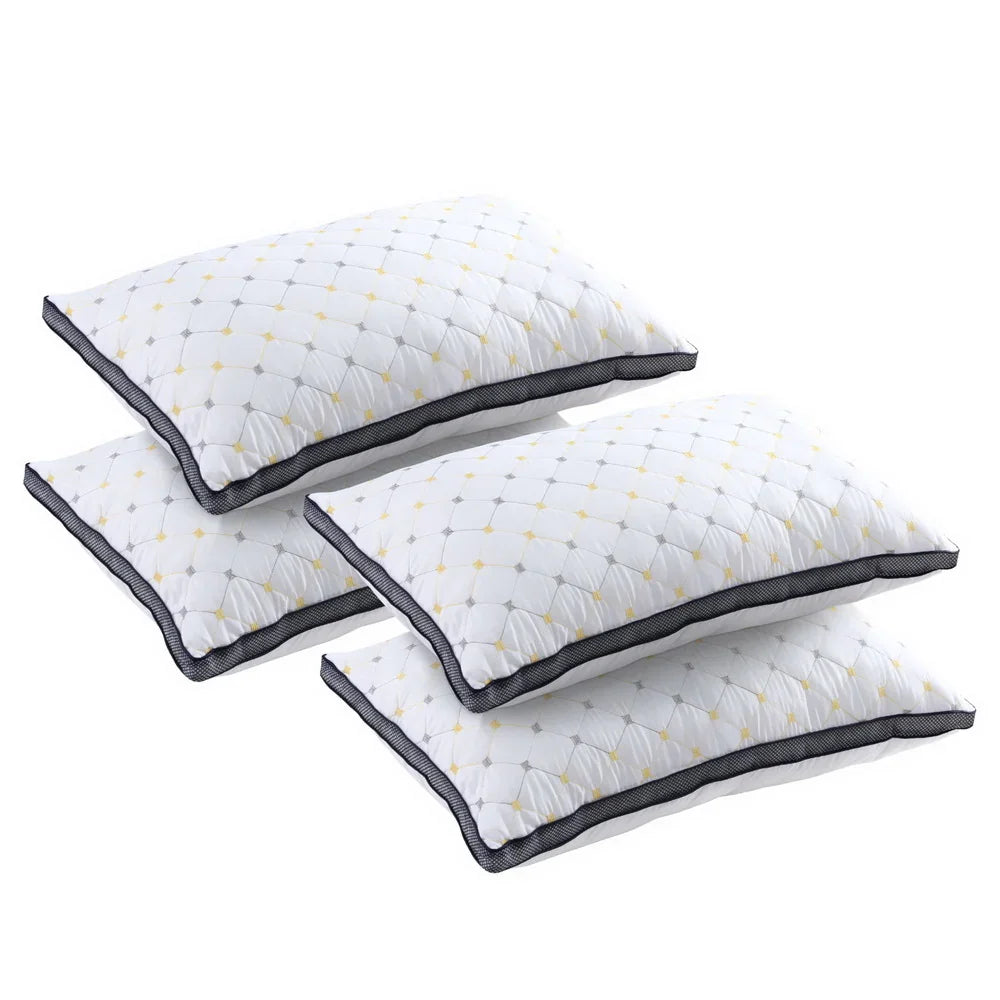 Set of four white quilted pillows with yellow and gray geometric pattern and black trim