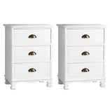 Pair of white three-drawer nightstands with brass cup handles on white background