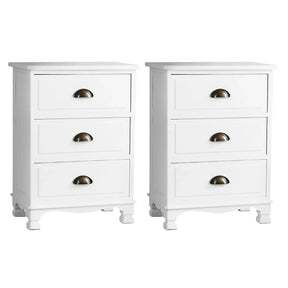 Pair of white three-drawer nightstands with brass cup handles on white background