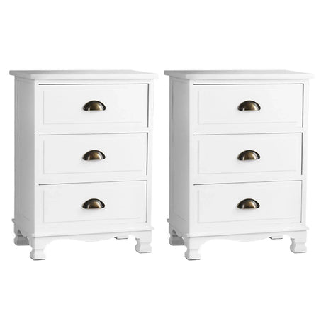 Pair of white three-drawer nightstands with brass cup handles on white background