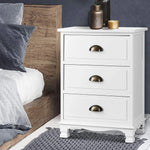 White 3-drawer nightstand with gold handles beside a wooden bed, modern bedroom decor