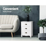 White three-drawer cabinet beside beige sofa, decorative vase on top, modern living room