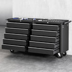 Black mobile tool chest with multiple drawers and hand tools on top against gray wall