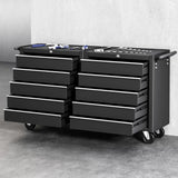 Black mobile tool chest with multiple drawers and hand tools on top against gray wall