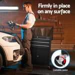 Mechanic working on automotive parts next to a white car with a black lockable caster tool cabinet