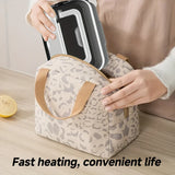 Person placing a black lunchbox into a beige patterned insulated bag on a kitchen counter