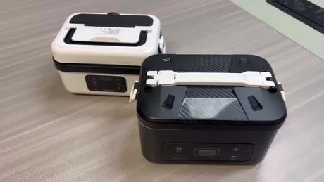 Two electric lunch boxes, black and white, on a table at Flea Market online store