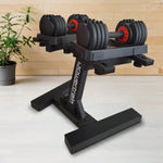 Adjustable black dumbbells on a sleek black stand with wooden wall and potted plant background