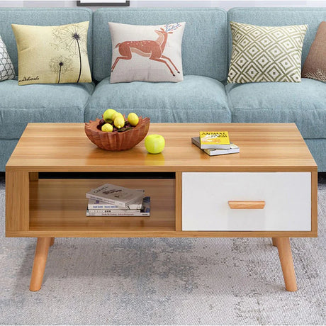 Modern wooden coffee table with drawer, fruit bowl, books, and blue sofa with cushions