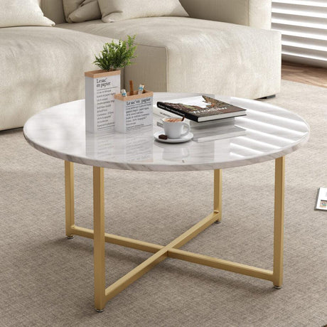 Modern round marble coffee table with gold metal legs in living room, books and coffee cup on top