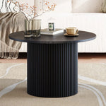 Modern black round coffee table with ribbed pedestal base, decor, and cozy living room setting
