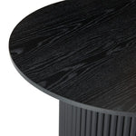 Round black wood dining table with ribbed cylindrical base and visible grain texture