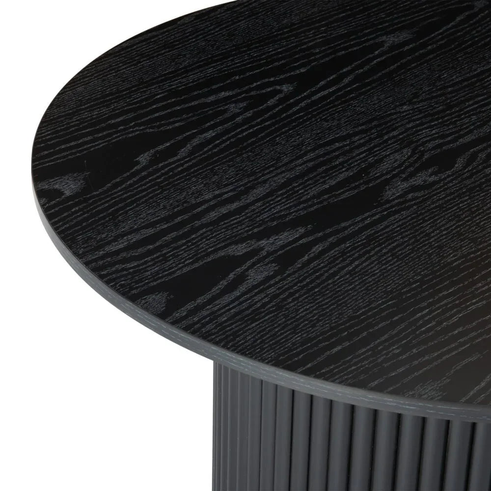 Round black wood dining table with ribbed cylindrical base and visible grain texture