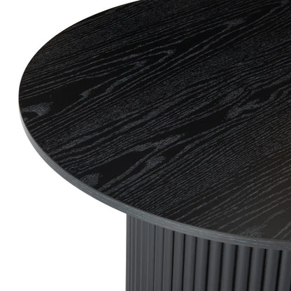 Round black wood dining table with ribbed cylindrical base and visible grain texture