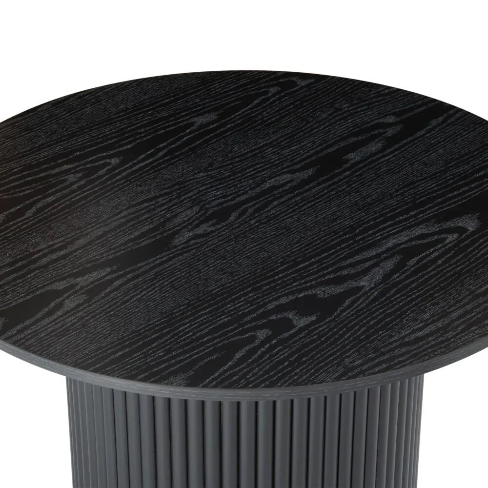 Round black wood dining table with fluted base and visible wood grain texture