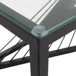 Black metal table corner with clear glass top and support cables, modern furniture detail