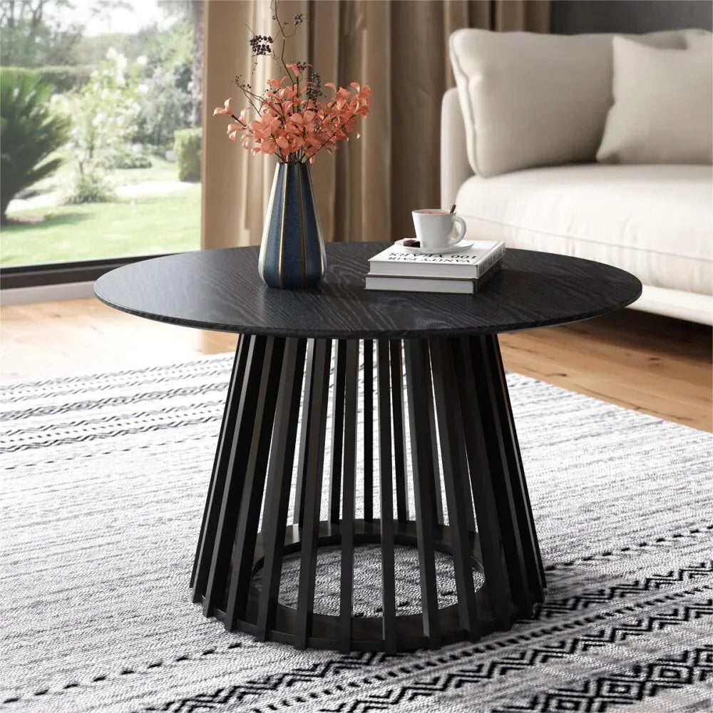 Modern black round coffee table with vase, book, and cup in a stylish living room