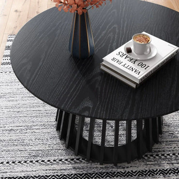 Modern black round coffee table with vase, books, and coffee cup on patterned rug