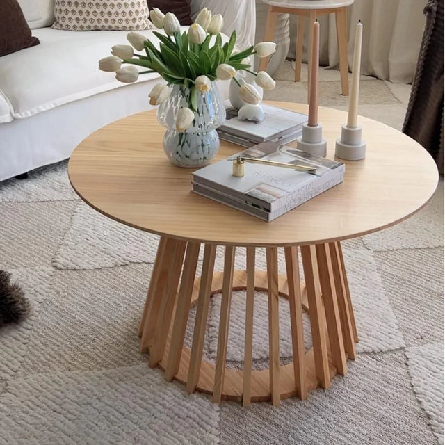 Modern wooden coffee table with tulip vase, candles, and books in cozy living room