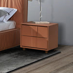 Modern brown leather nightstand with two drawers beside a bed on wood floor