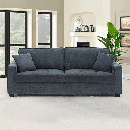 Modern dark gray sofa with two pillows in a bright living room with fireplace and plant