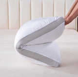 Hand folding a white pillow with gray mesh breathable sides on a beige bed